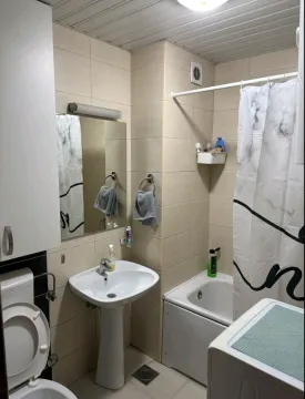 Smaller bathroom with a washbasin, shower, and toilet. - image 6