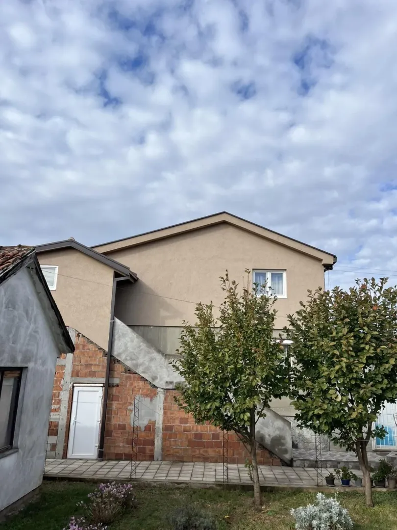 Spoljašnjost dvospratne kuće sa dvorištem.