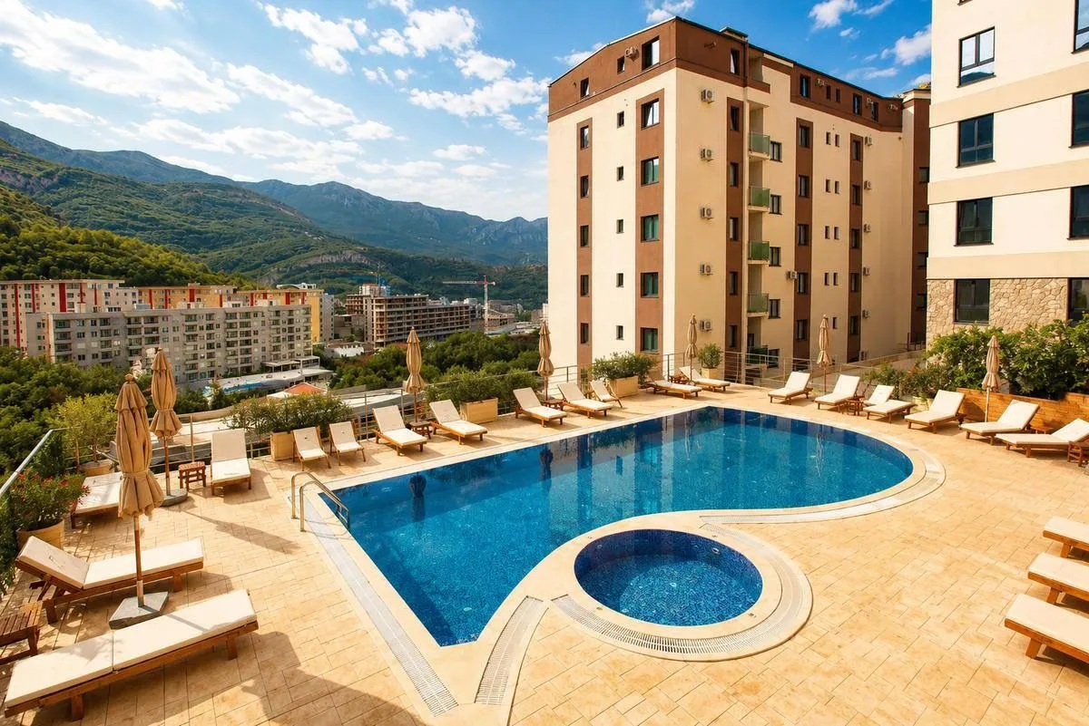 Outdoor area with a swimming pool and sun loungers in front of an apartment building.