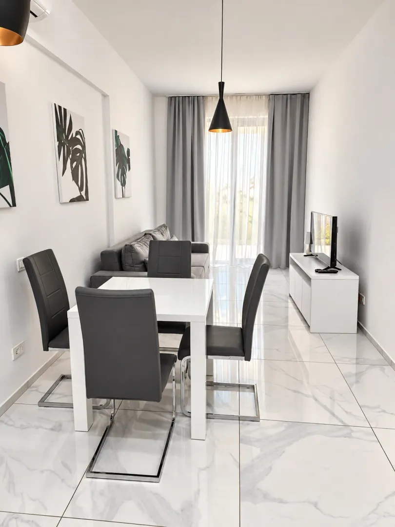 Living room with a dining area, sofa set, and white tiled flooring.