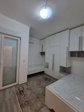 Bright bedroom featuring built-in white wardrobes and two single beds. - image 6