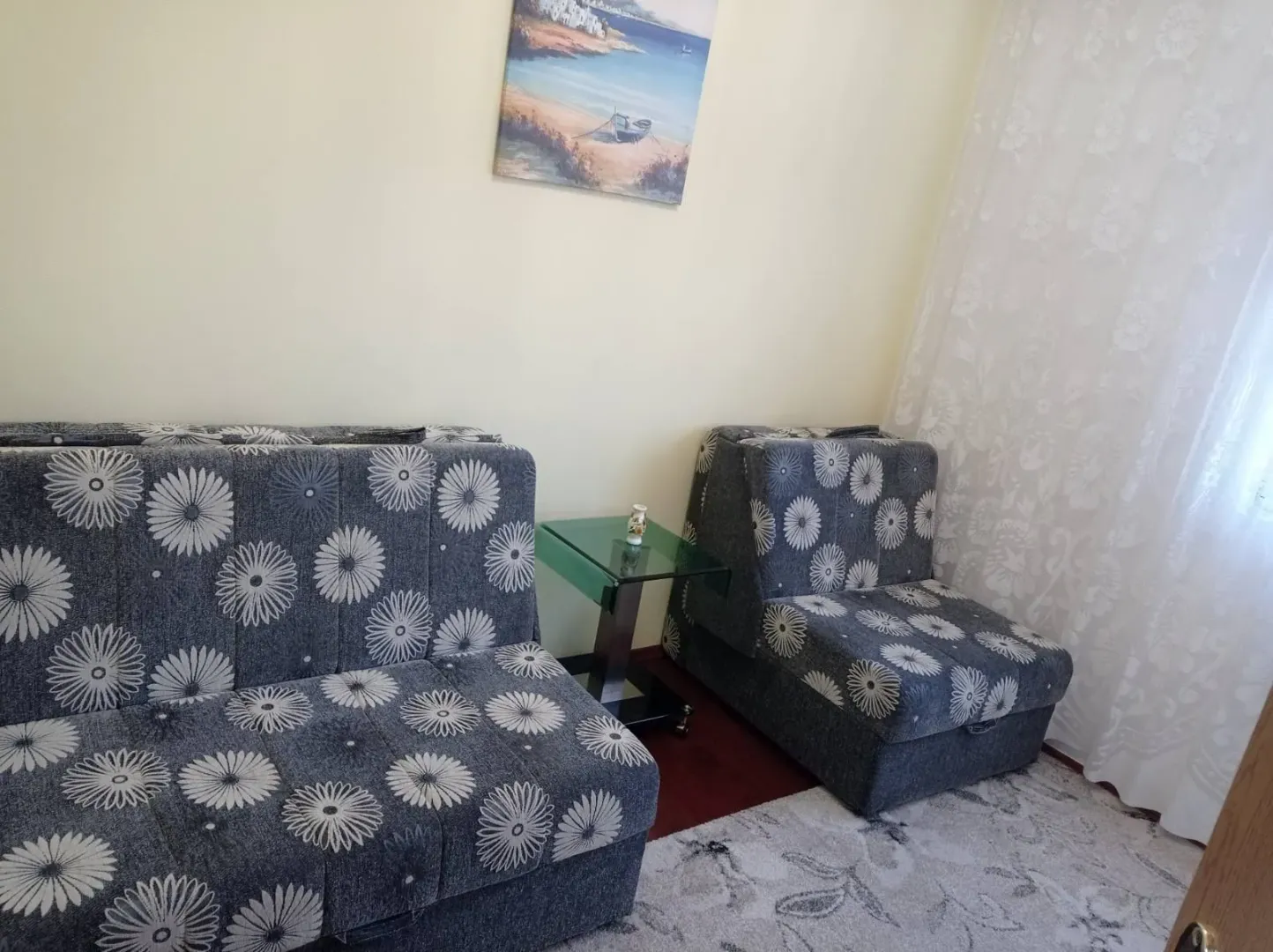 A living room with flower-patterned seating and a small glass side table.