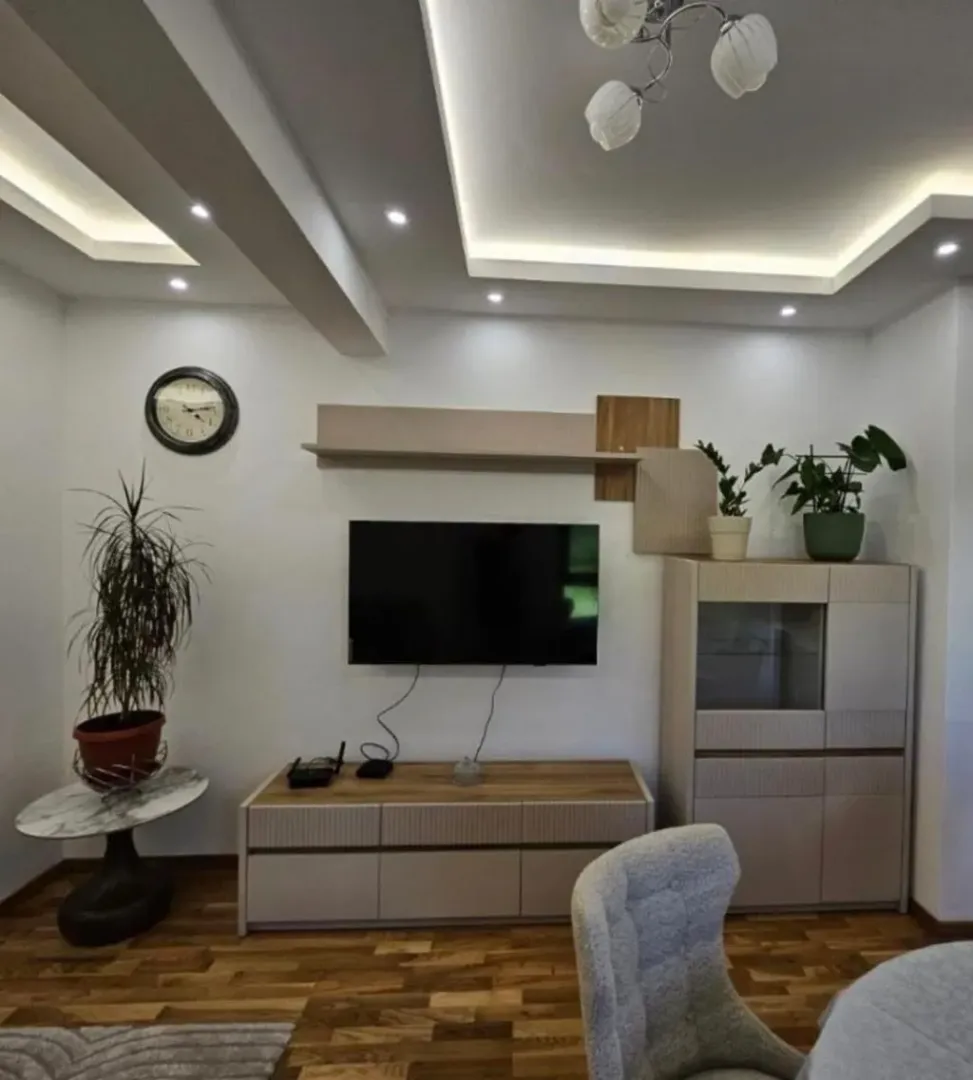 Modern living room with a TV unit and dropped ceiling with lighting.