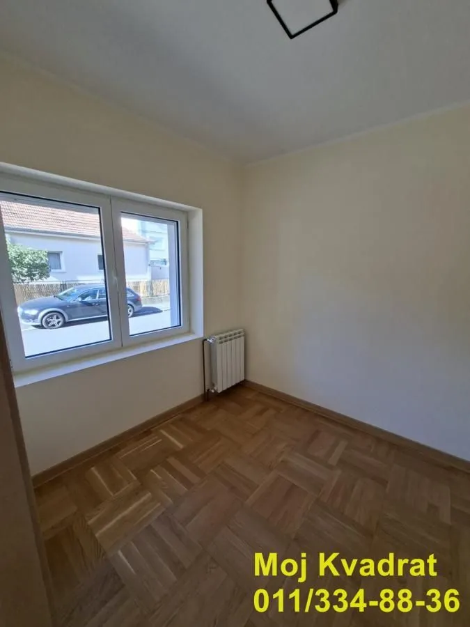 Prazna soba sa parketom i prozorom.