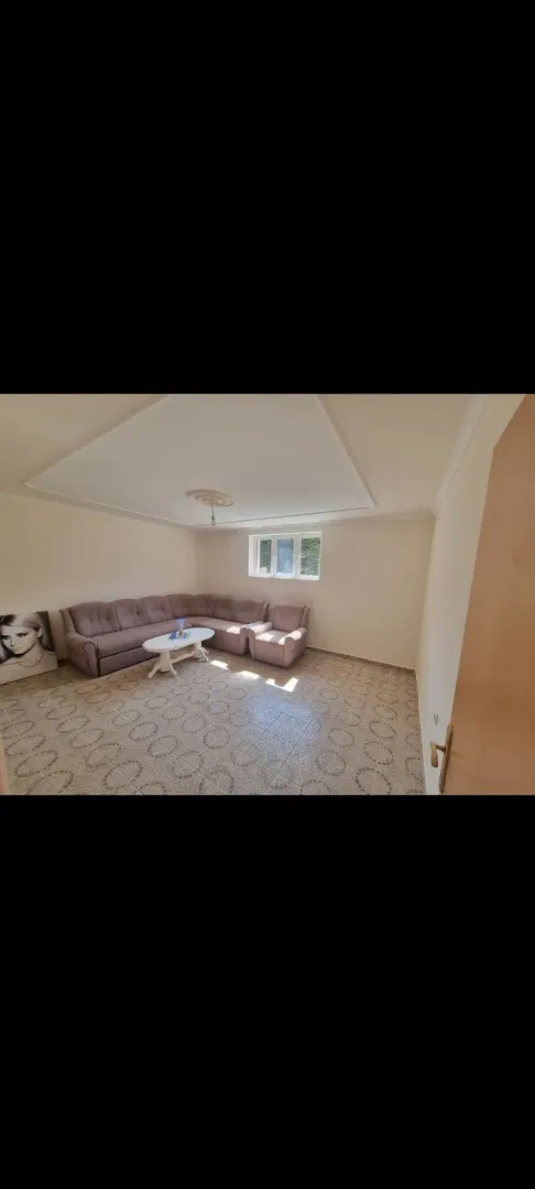 Bright living room with a corner sofa and tiled floor.