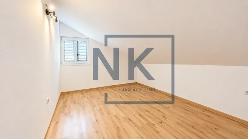 Empty attic room with laminate flooring and white walls.