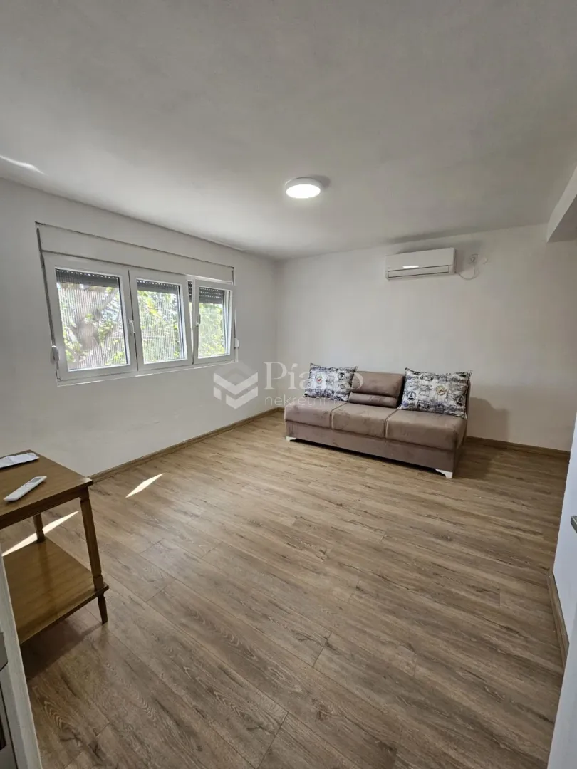 Living room with a sofa, wooden flooring, and a window.