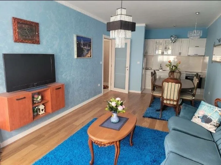 Bright living room with blue walls, dining area, and kitchen in the background.