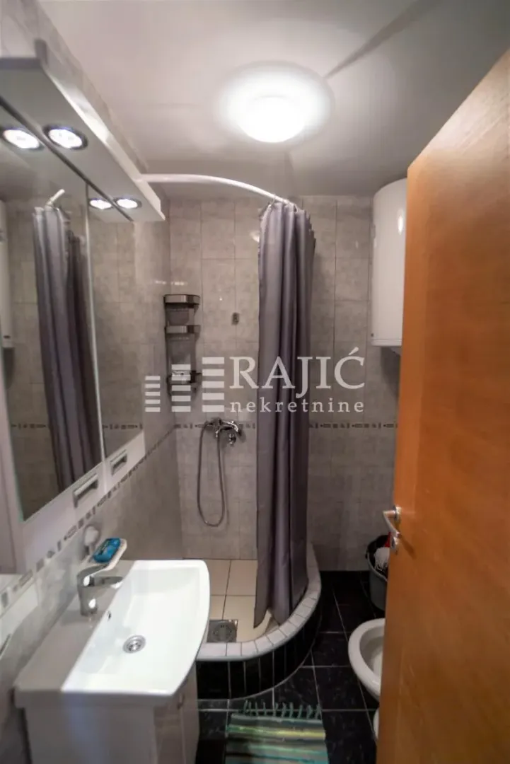 Small bathroom with a shower cabin, washbasin, and mirror.