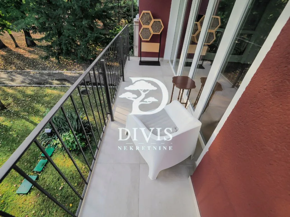 Small furnished balcony with metal railing and green view.