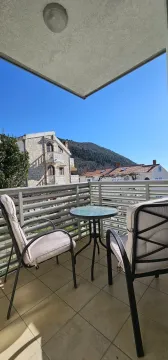Covered terrace with seating furniture and a view of surrounding buildings and a hill. - image 12