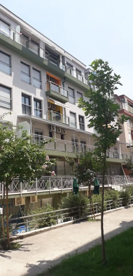 Exterior of a residential building with balconies and trees.