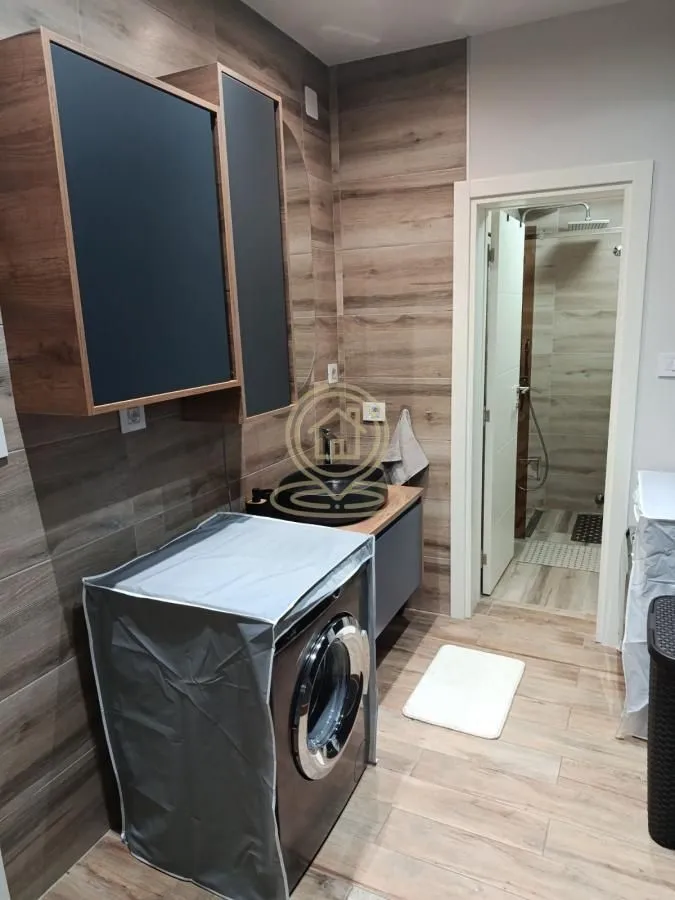 Bathroom with washbasin, washing machine and walk-in shower.
