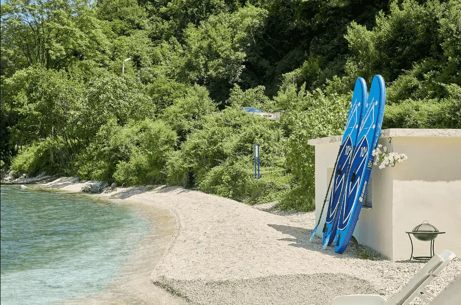 Plaža sa daskama za veslanje ispred objekta u zelenilu.