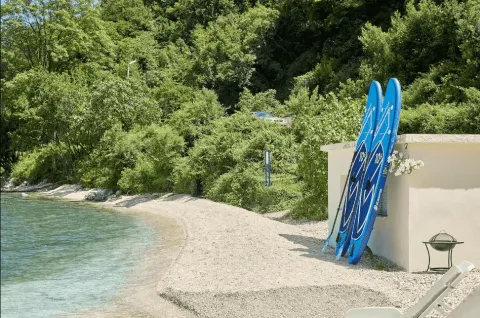 Plaža sa daskama za veslanje ispred objekta u zelenilu. - image 5