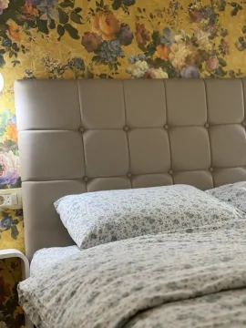 Krevet sa tapaciranim uzglavljem i cvjetnim tapetama u spavaćoj sobi. - image 6