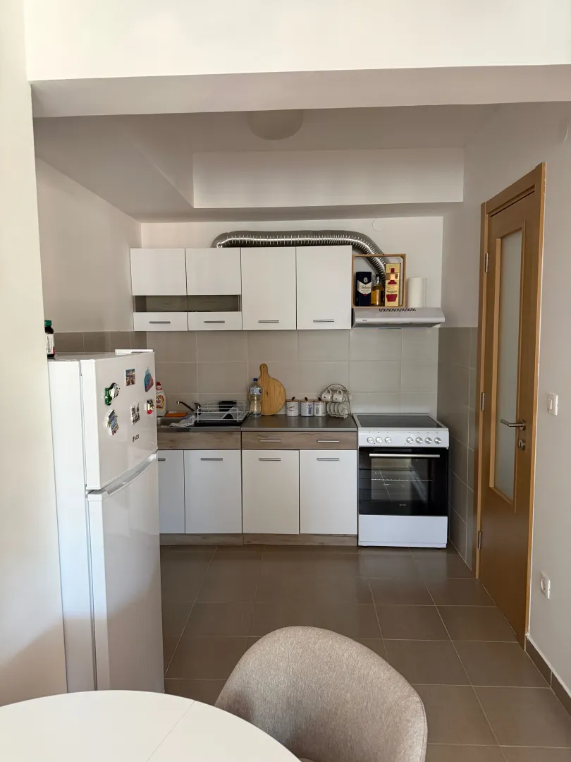 Small white kitchen equipped with necessary appliances and a refrigerator.