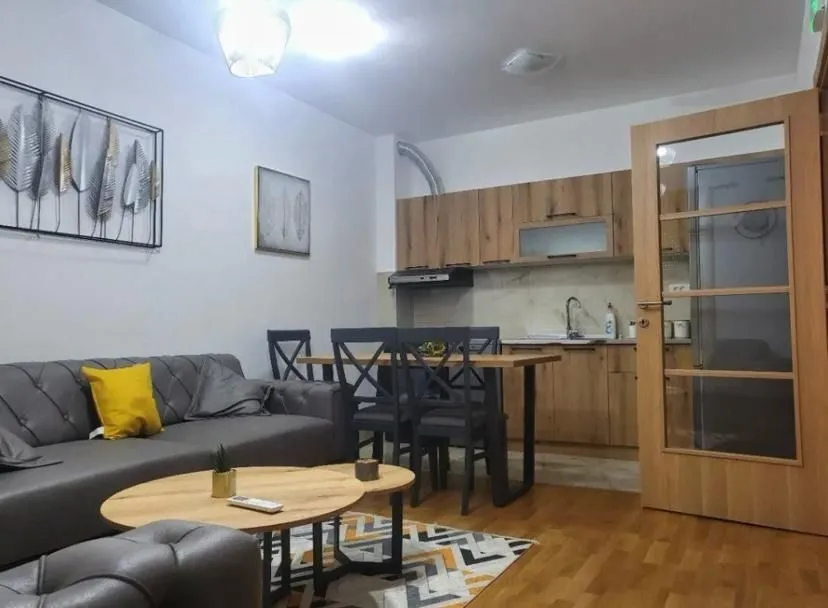 Living room with a sofa, dining table, and kitchen in the background.