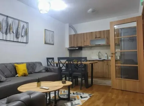 Living room with a sofa, dining table, and kitchen in the background. - image 6