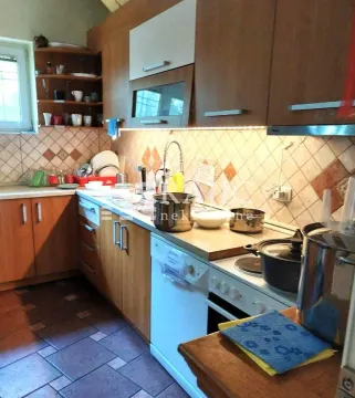 Smaller kitchen with wooden cabinets and tiled walls. - image 14