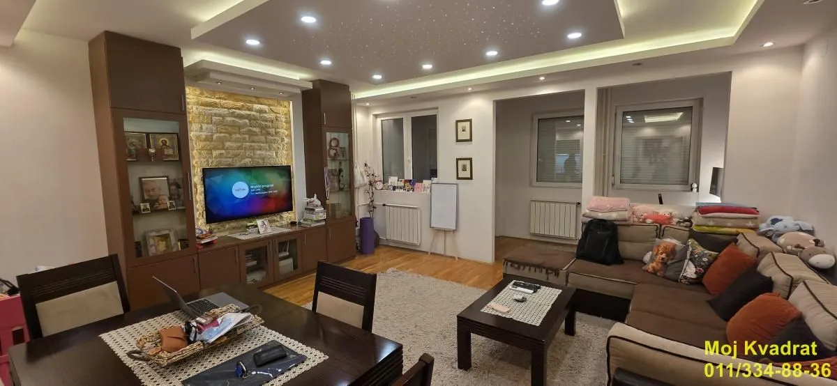 Dnevna soba sa garniturom, trpezarijskim stolom i TV komodom.