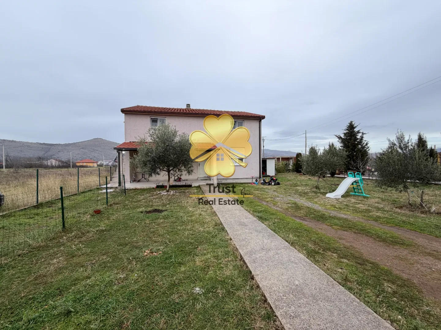Two-story family house with a landscaped yard and pathway.