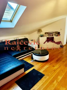 Attic living room with a black leather sofa and a skylight. - image 2