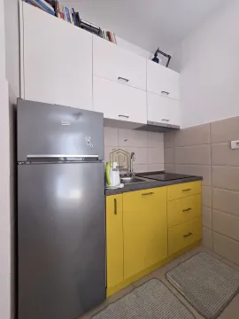 Manja kuhinja sa žutim elementima, bijelim visećim dijelovima i frižiderom. - image 4