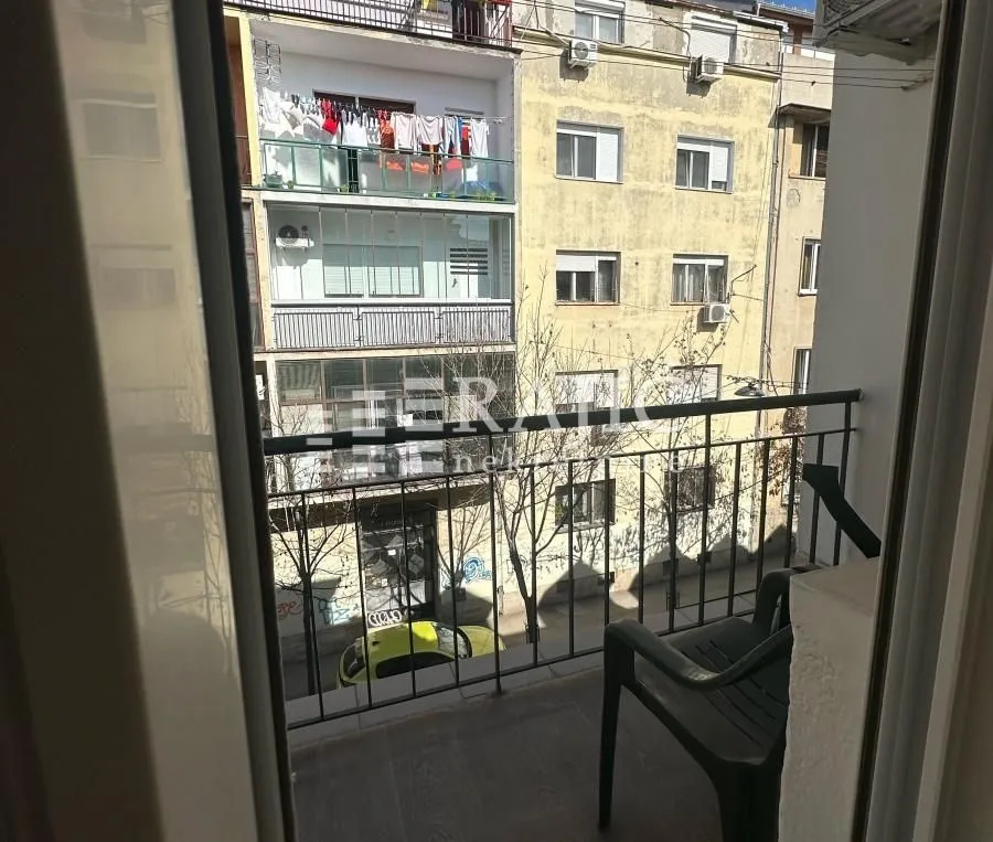 Small balcony with a chair and a view of surrounding buildings.