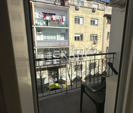 Small balcony with a chair and a view of surrounding buildings. - image 7