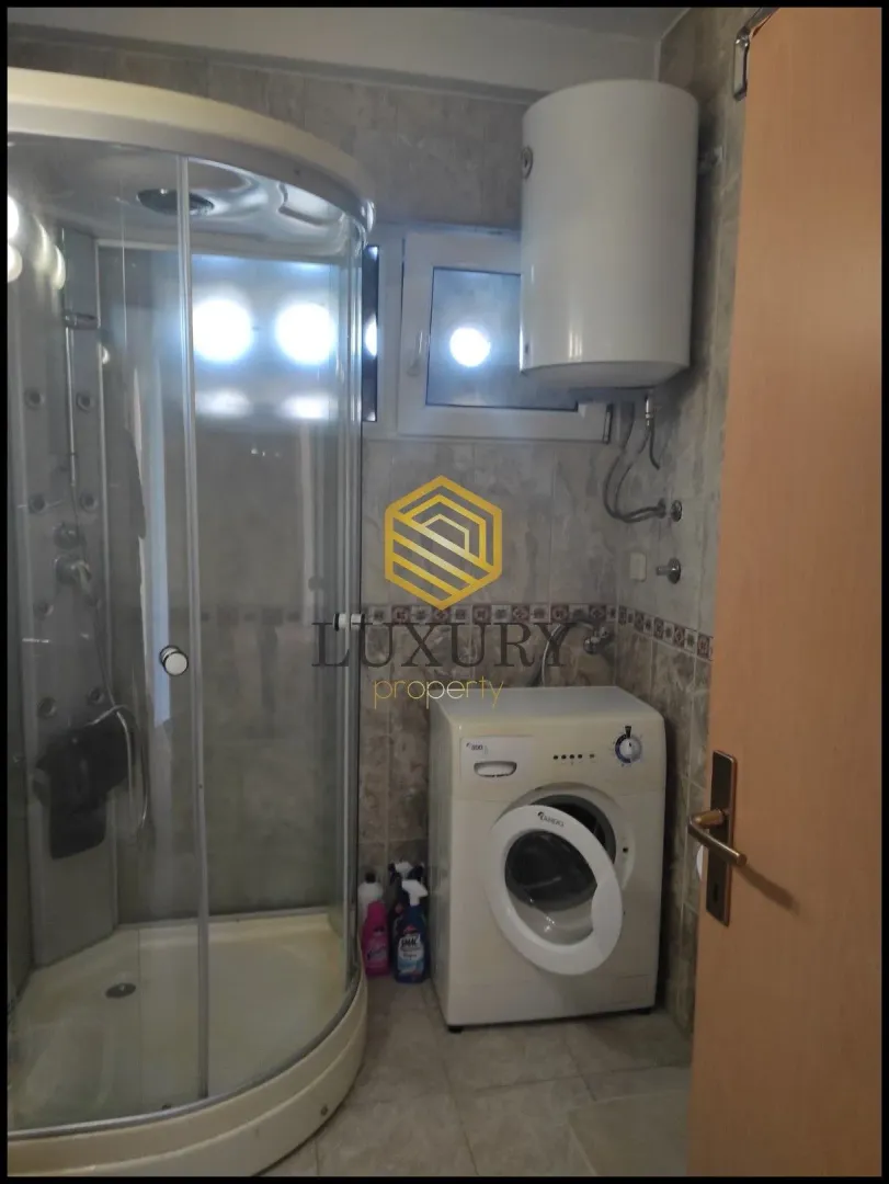 Small bathroom with a shower cabin, water heater, and washing machine.