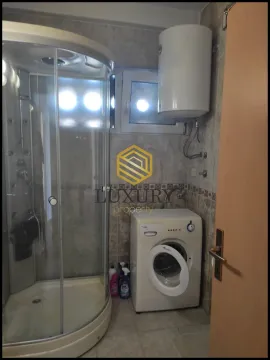 Small bathroom with a shower cabin, water heater, and washing machine. - image 12