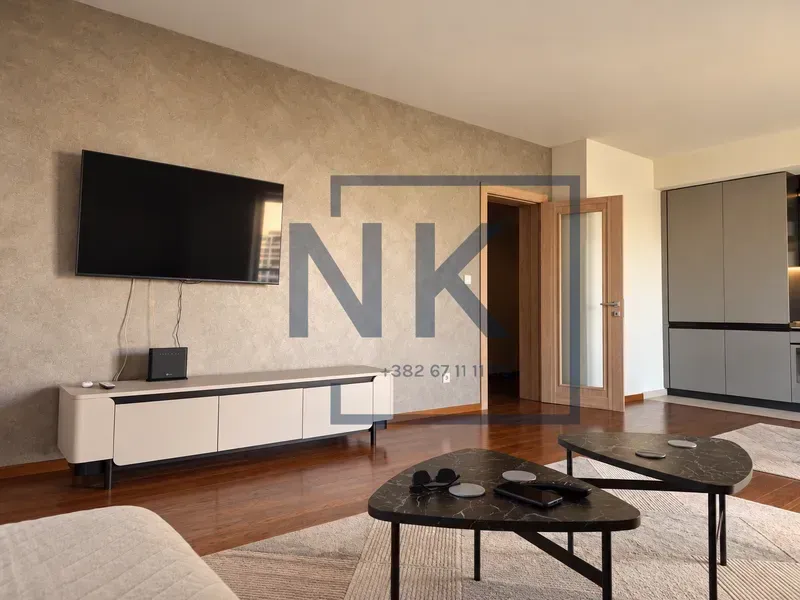 Living room with sofa, television, and coffee tables.
