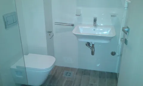 Small bathroom with a wall-mounted toilet and a sink. - image 6