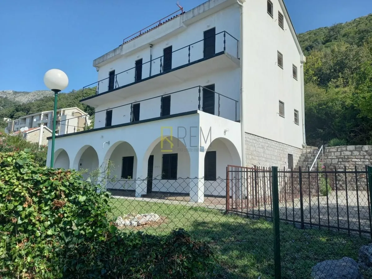 Eksterijer višespratne bijele kuće sa terasama i dvorištem.
