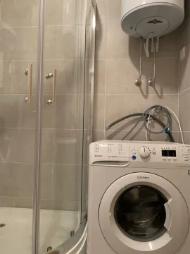 Bathroom with a shower cabin, washing machine, and water heater. - image 6