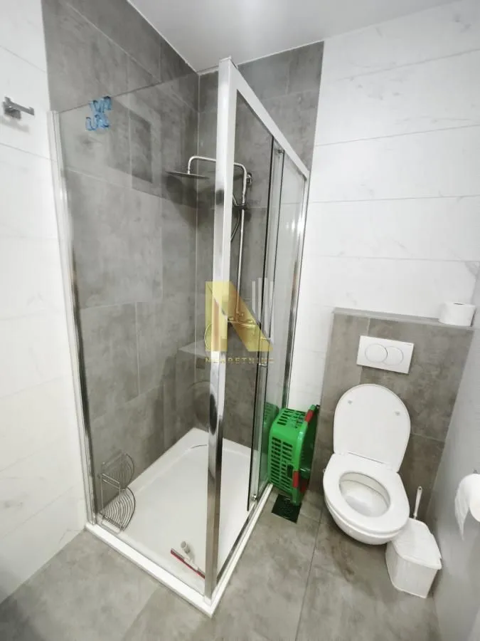 Moderno kupatilo sa tuš kabinom i sanitarijama.