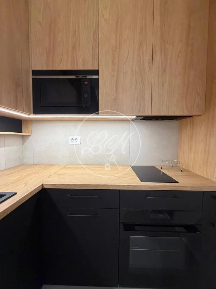 Part of the kitchen with wooden elements, built-in oven and microwave.