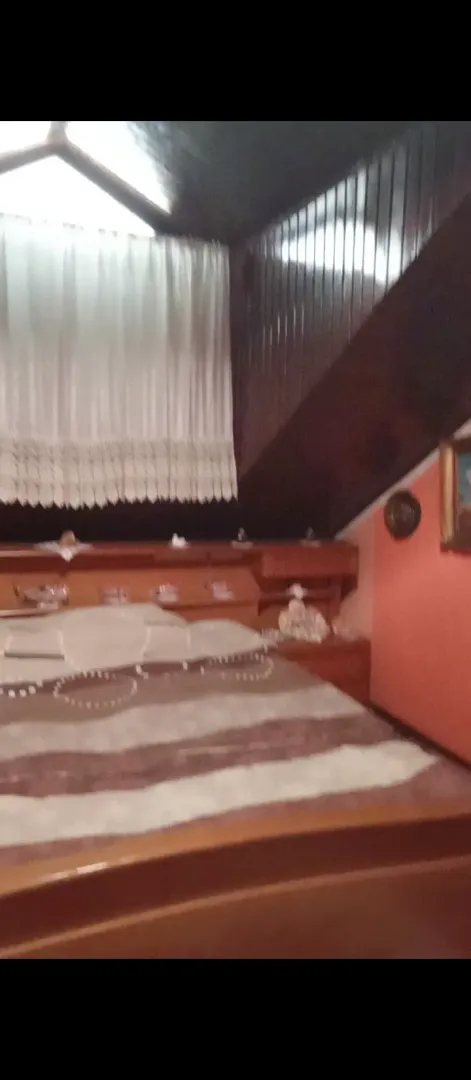 Spavaća soba sa bračnim krevetom i drvenim oblogama na zidu i plafonu.