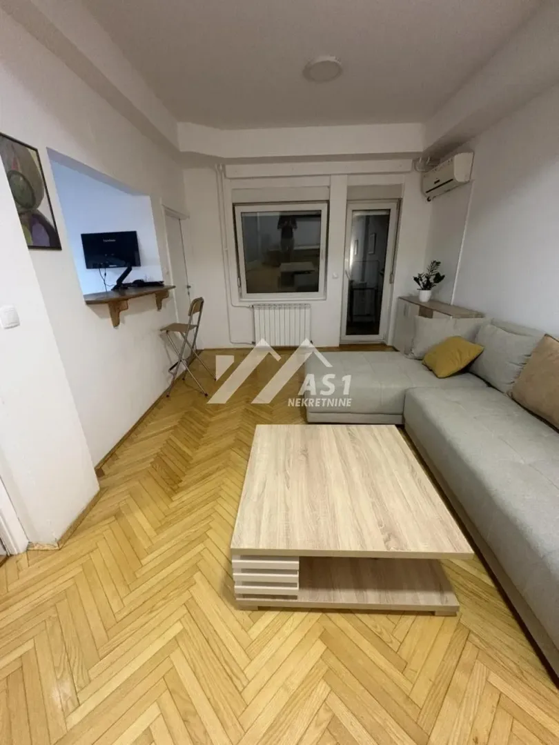 Dnevna soba sa ugaonom garniturom, drvenim stočićem i parketom.