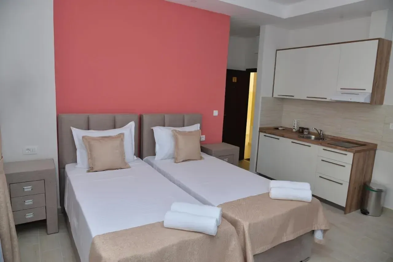 Bedroom with two single beds and a small kitchen in the corner.