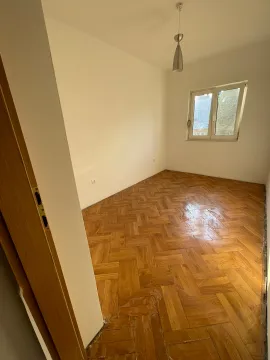 Empty room with parquet flooring and a single window. - image 3