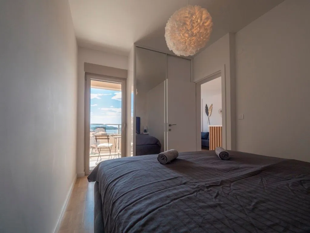 Bedroom with a double bed and access to a terrace with a sea view.