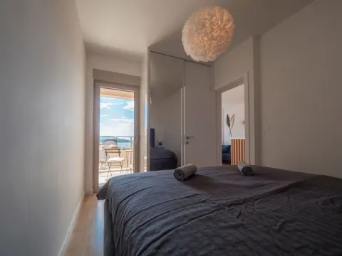 Bedroom with a double bed and access to a terrace with a sea view. - image 7