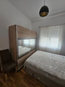 Furnished bedroom with a double bed, large wardrobe, and window with curtains. - image 8