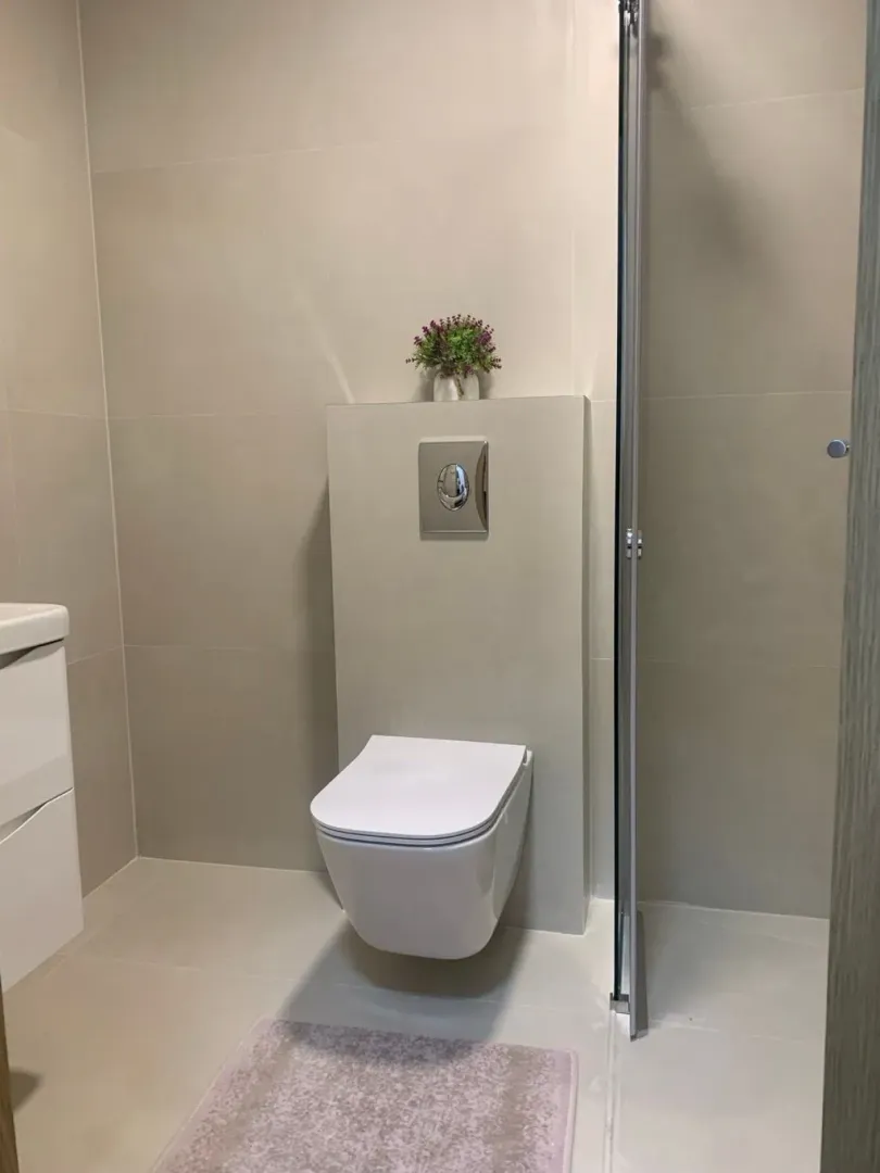 Moderne kupatilo sa konzolnom šoljom, umivaonikom i tuš kabinom.