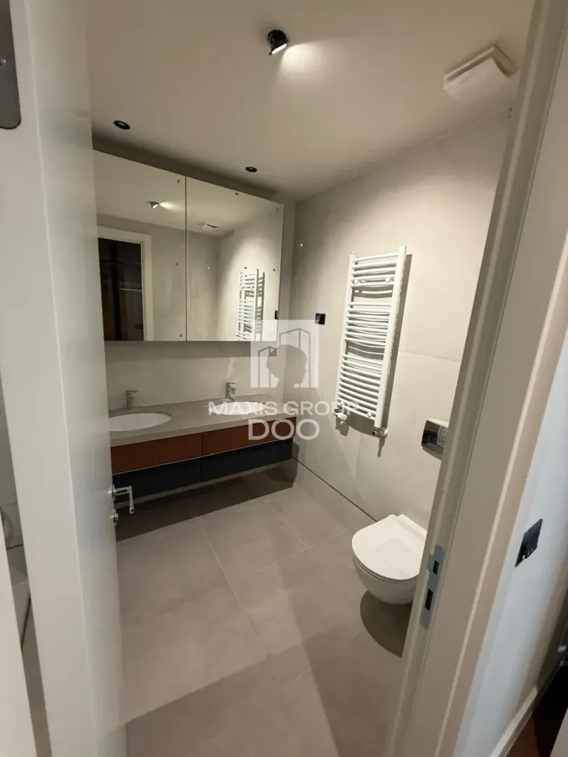 Moderno opremljeno kupatilo sa umivaonikom, ogledalom i WC šoljom.
