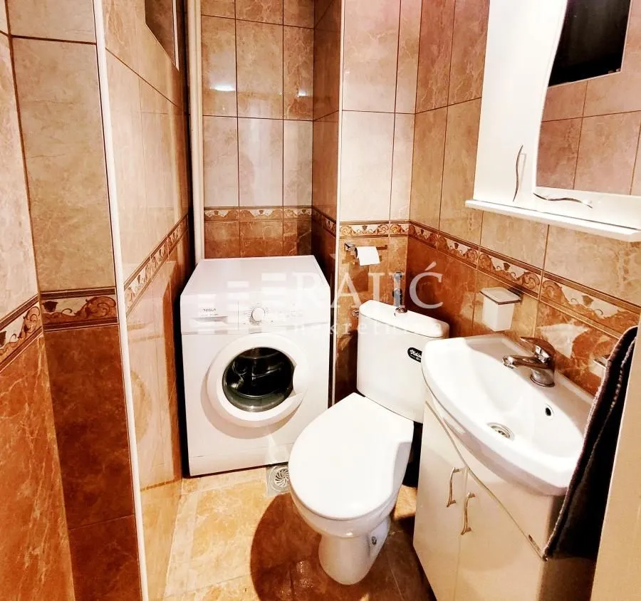 Kupatilo opremljeno sanitarijama i veš mašinom.