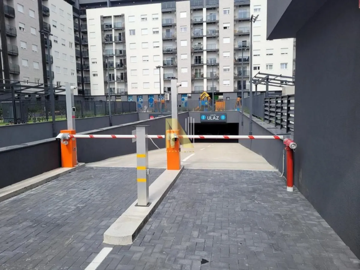 Entrance to the underground parking garage with a ramp and residential building in the background.