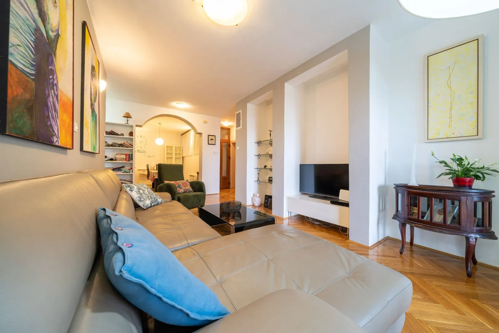 Spacious and bright living room with a leather sofa and hardwood flooring.